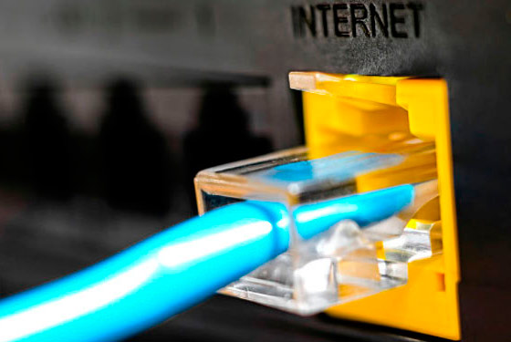 imagem de um cabo de internet conectado na parte de trás de um computador