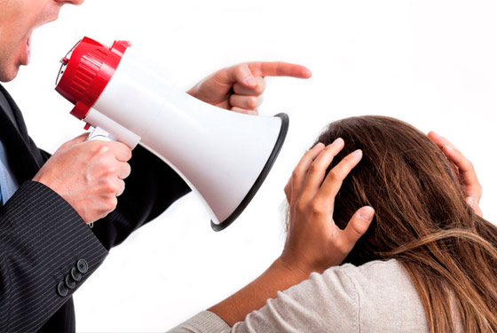 Homem com megafone na boca gritando para uma mulher com as mãos tapando as orelhas