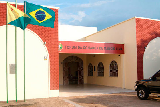 imagem da fachada do fórum da cidade de Mâncio Lima com duas bandeiras hasteadas, a do Brasil e do Acre.