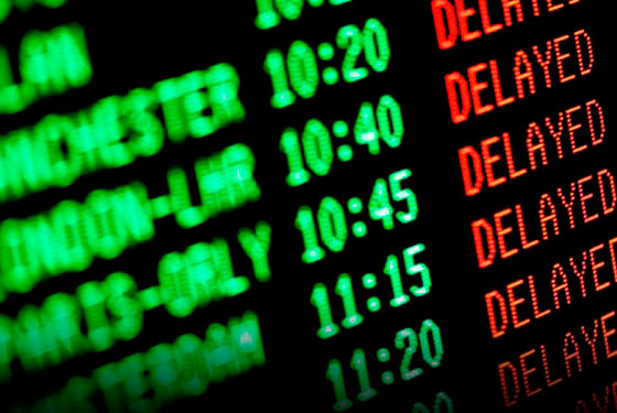 imagem de um painel de aeroporto com nomes de voos, horários e escrito a palavra inglesa"delayed", que significa atrasado