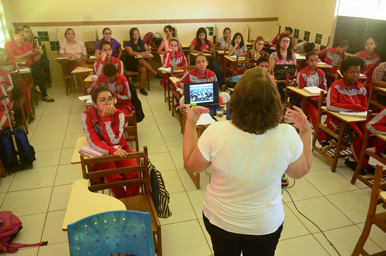 Imagem de uma professora falando com uma sala de aula de alunos