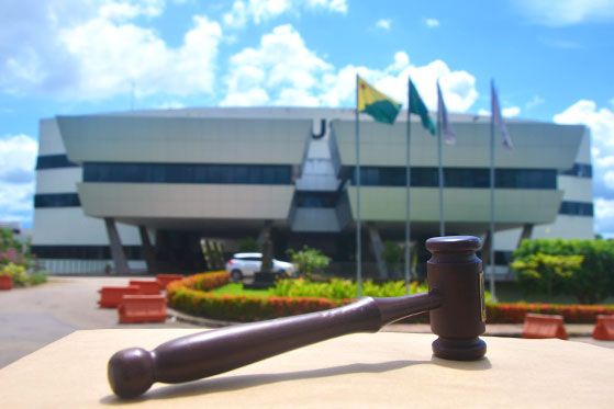 foto do martelo de juiz sobre superfície marrom a frente do prédio sede do TJAC.