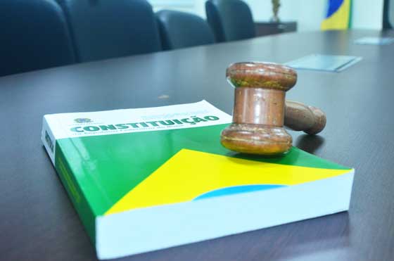 foto de um martelo de juiz em cima do livro da Constituição brasileira