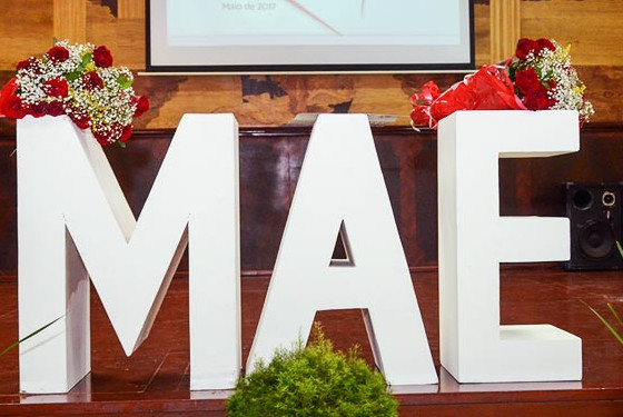 Foto de letras gigantes escrito "Mãe". As letras estão posicionadas no palco do auditório do Palácio de Justiça