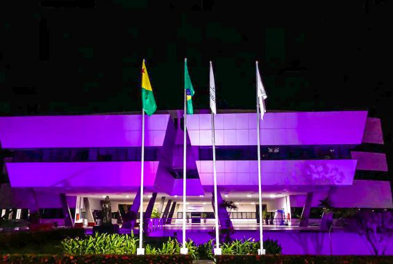 Fotografia da sede do Tribunal de Justiça do Acre, mostrando a que o prédio está iluminando na cor lilás