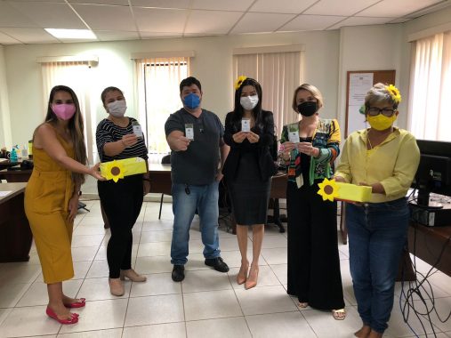 Equipe da Gerência de Qualidade de Vida ao lado dos servidores do setor de comunicação do TJAC posando para foto. Todos seguram saquinhos com folhas de chá