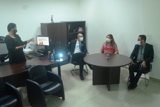 foto da diretora de gestão de pessoas de pé ao lado do data show, falando com o vice-presidente do TJAC, desembargador Roberto Barros, a presidente, desembargadora Waldirene Cordeiro e o juiz de Direito auxiliar da presidência, Leandro Leri Gross