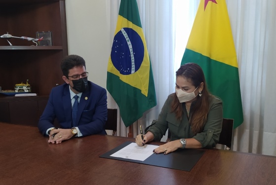 Foto da desembargadora Waldirene sentada no salão de reunião do Estado assinando o termo de transmissão do cargo de governador