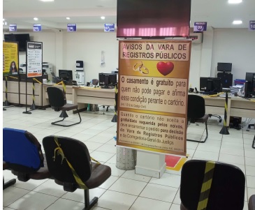 Imagem da sala de espera de outro cartório com um banner informando sobre a gratuidade no casamento para casais carentes