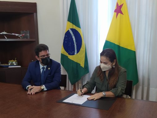 Foto da desembargadora Waldirene sentada no salão de reunião do Estado assinando o termo de transmissão do cargo de governador