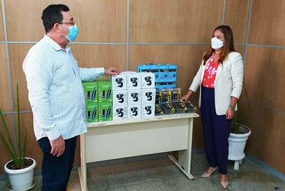 Foto da presidentes do TJAC recebendo equipamentos de tecnologia. De frente para a presidente um servidor com o abraço em cima das caixas dos equipamentos que estão em cima de uma mesa.