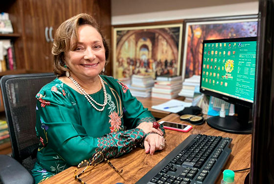 Foto da desembargadora Eva sentado na mesa do computador, olhando e sorrindo para foto