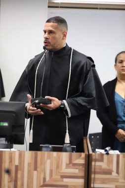 Juiz segurando um microfone. Vestido de preto. 