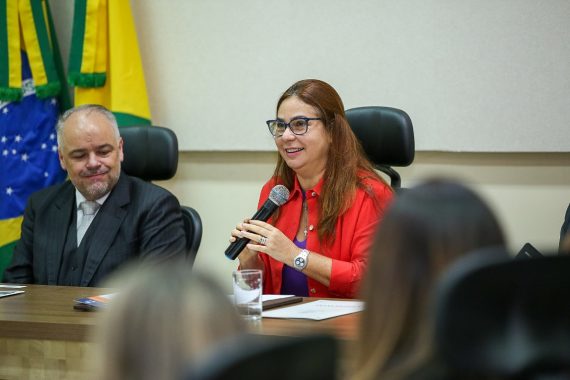 Foto da desembargadora Waldirene Cordeiro vestida de vermelho falando ao microfone