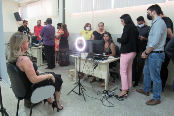 foto de pessoas ao retor de uma mesa e uma mulher sentada posando para foto