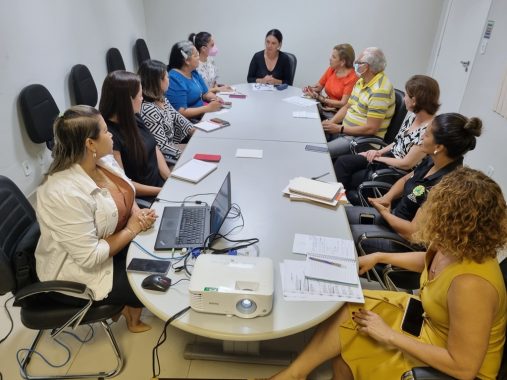 Foto da mesa de reunião e as pessoas sentadas em volta conversando