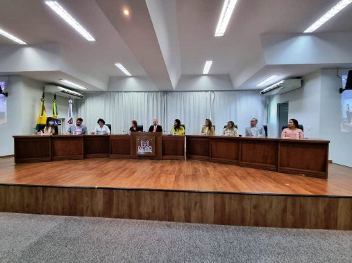 10 pessoas sentadas no dispositivo de honra do auditório do Ministério Público