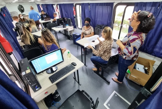 Foto do ônibus da Justiça com mesas, servidores e servidoras atendendo