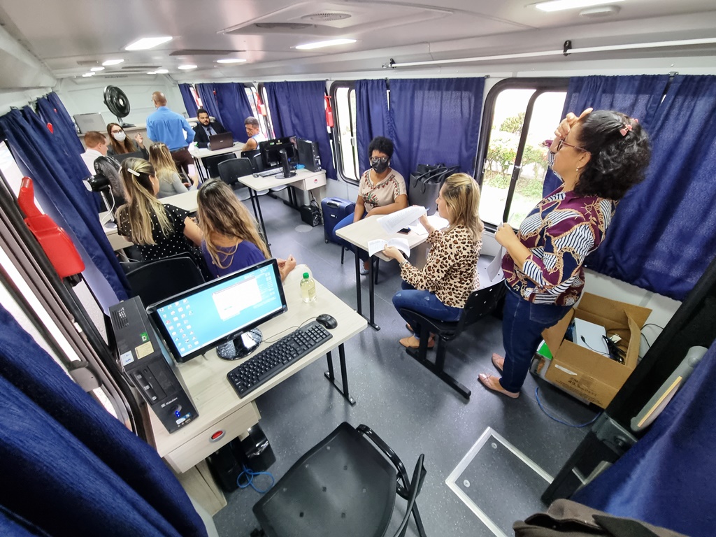 Foto do ônibus da Justiça com mesas, servidores e servidoras atendendo