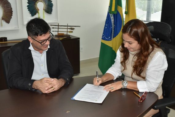 Foto da desembargadora Waldirene Cordeiro assinando ordem de serviço com secretário da seinfra olhando