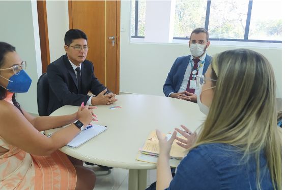 Foto de quatro pessoas sentadas em volta de uma mesa redonda conversando