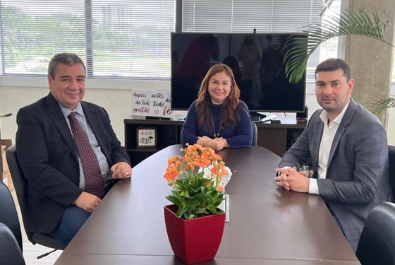 Desembargadora sentada sorrindo. Desembargador sentado ao lado direito dela e o deputado sentado ao lado esquerdo.