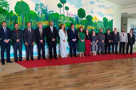 Quinze pessoas em frente a um painel pintado com tema de floresta