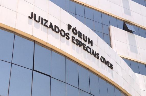 Fachada do prédio escrito: Fórum Juizados Especiais Cìveis. O prédio é branco e com janelas de vidro