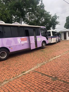 Fotografia dos ônibus da Patrulha Maria da Penha e do Pacto Nacional pelo Enfrentamento à Violência contra a Mulher no estacionamento da escola Sebastião Pedrosa