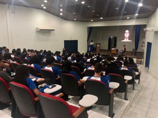 Fotografia do fundo do auditório com os alunos assistindo a vídeo sobre violencia domestica projetado na parede 