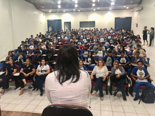 140 alunos assistindo palestra sobre violência doméstica no auditório da Escola Sebastião Pedrosa