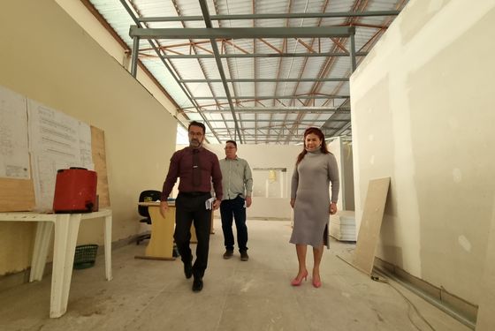 Três pessoas caminhando em um corredor de uma obra