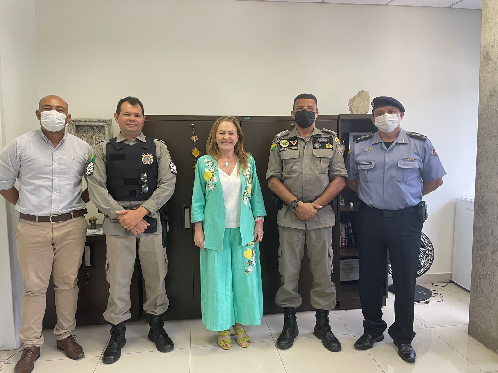 Fotografia no gabinete da desembargadora Regina Ferrari. Ela está ao centro com um terno verde e ao seu lado estão quatro militares