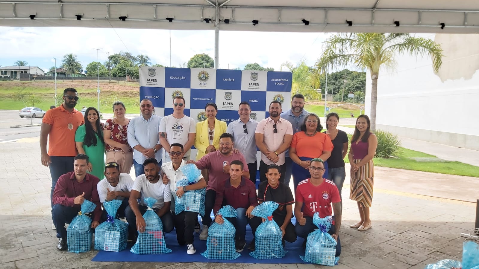 Foto de seis presos do semiaberto que receberam kits de barbeiro. Logo atras deles estão os servidores do Iapen, policiais penais, a juíza Andrea Brito e o promotor de justiça Tales Tranin