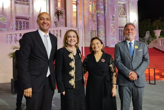 Foto de dois desembargadores e duas desembargadoras em linha, olhando para foto. Eles estão na frente do Palácio do governo