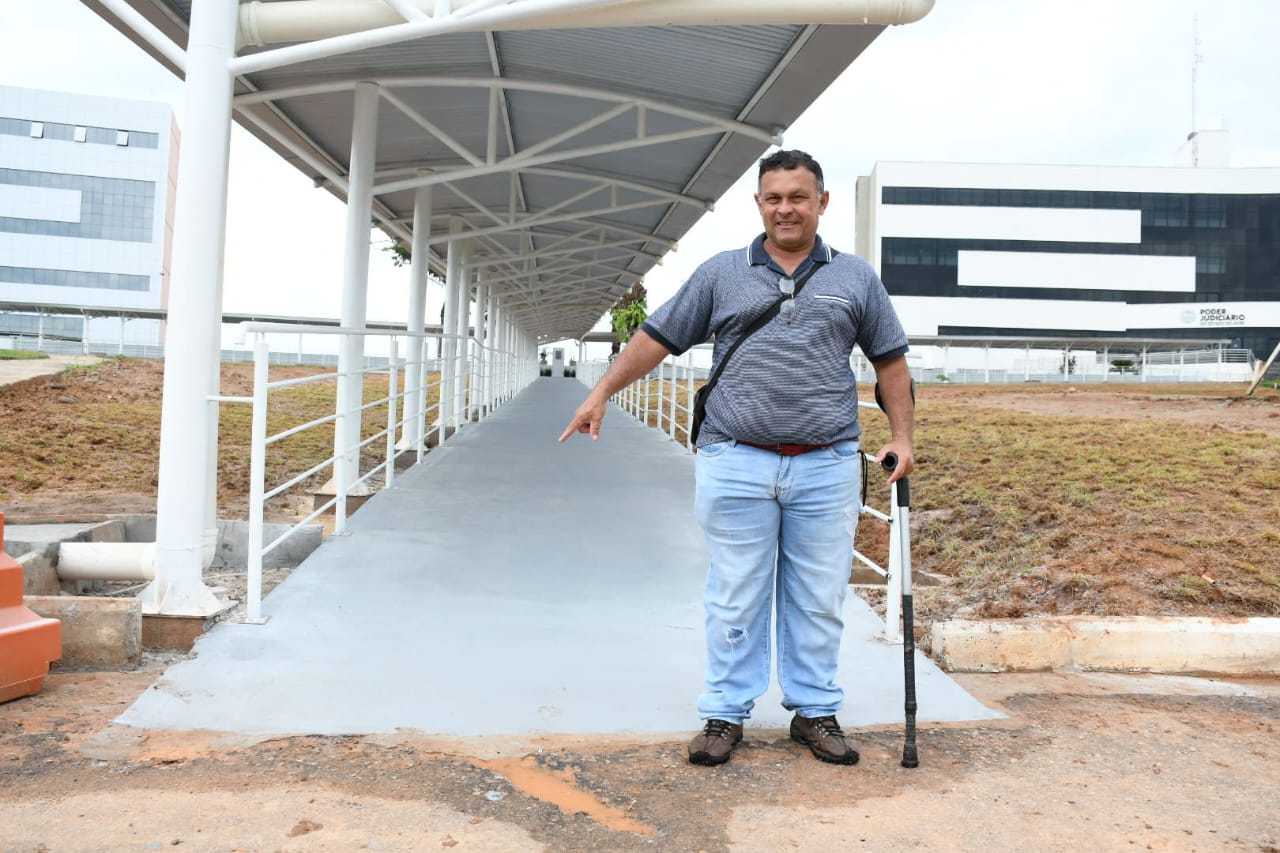 Foto de um cidadão com muleta ao lado do início da passarela situada na Cidade da Justiça de Rio Branco