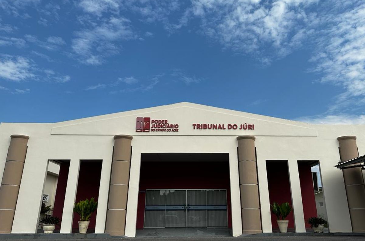 Fachada do prédio do Tribunal do Júri de Cruzeiro do Sul. O Prédio tem uma fachada em triangulo, colunas redondas, está pintado na cor bege com logomarca e nome do local na cor vermelho escuro