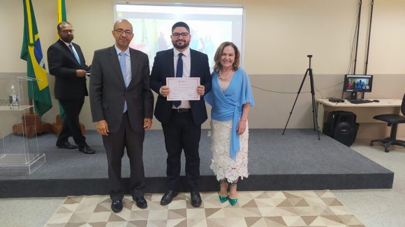 Fotografia do juiz substituto recebendo certificado de conclusão da formação inicial ofertada pela Esjud