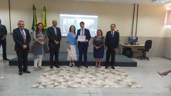 Fotografia do juiz substituto Mateus Pieroni recebendo certificado de conclusão da formação inicial ofertada pela Esjud