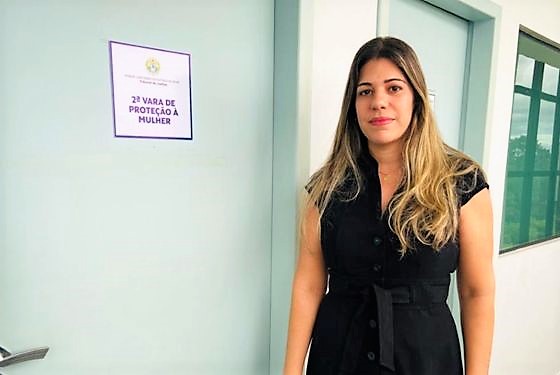 Fotografia da juíza Louise Kristina em frente à porta da 2ª Vara de Proteção à Mulher, onde ela passará a atuar a partir de abril de 2023.