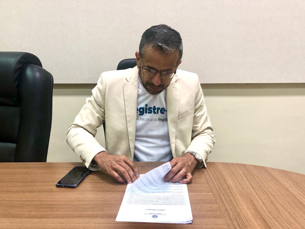 Foto do juiz Edinaldo Muniz assinando o Termo de Compromisso de apoio ao evento "Registre-se"