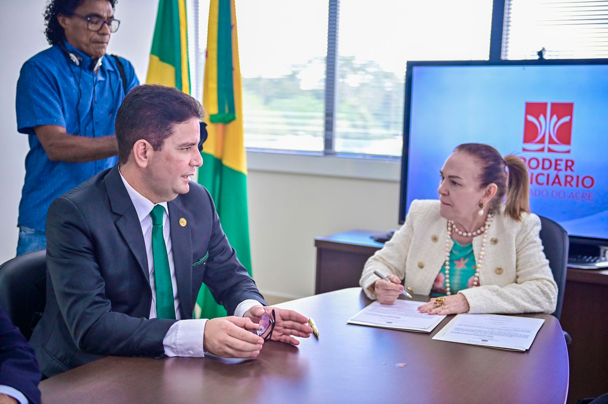 Foto do governador Gladson Cameli e a desembargadora Regina Ferrari na conversando na mesa da presidência