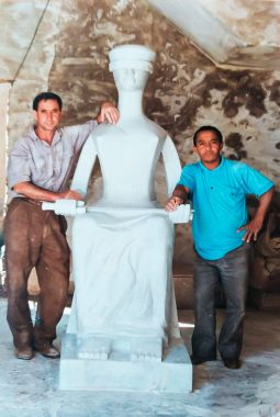 Foto do artista João Matias e seu assistente Mário Calango ao lado da estátua da deusa Themis pronta, ela foi encomendada para o Fórum Barão de Rio Branco