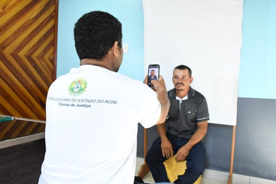 Servidor tirando foto 3x4 de um homem para a confecção de documentos.