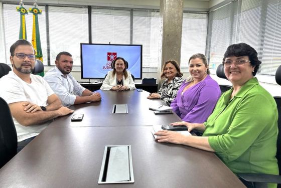 A desembargadora-presidente, Regina Ferrari, está sentada à mesa junto a desembargadora Eva Evangelista, o prefeito de Jordão e os demais presentes na reunião, suas respectivas equipes.