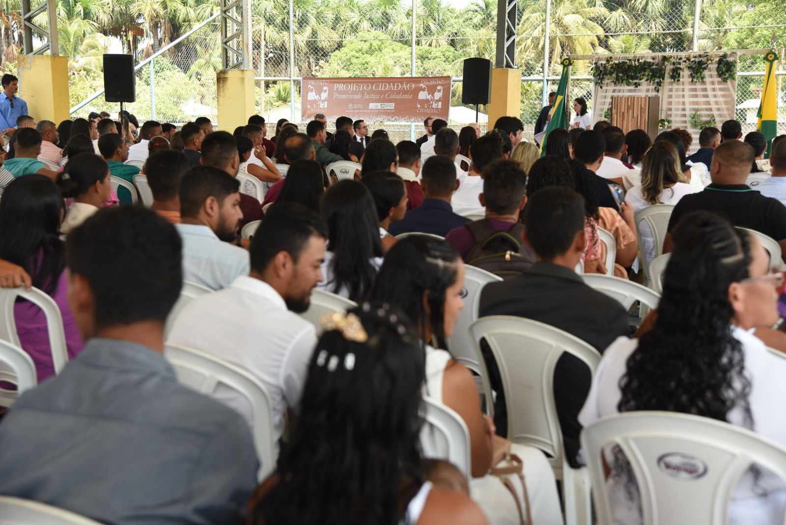 Grupo de casais aguardam o casamento. Todos se encontram sentados.