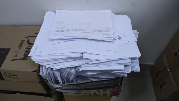Foto de caixas acumulando papéis no departamento da Central de Mandados