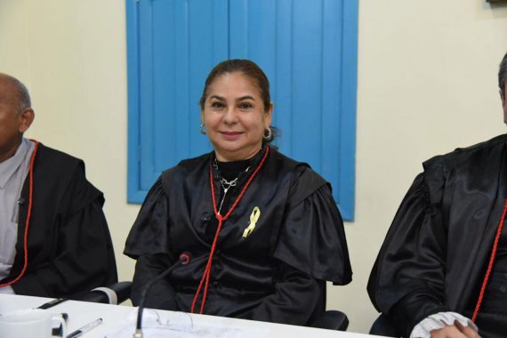 Foto da desembargadora Waldirene Cordeiro. Ela está sentada e sorrindo. Ela está usando toga e está no Centro Cultural do Juruá.