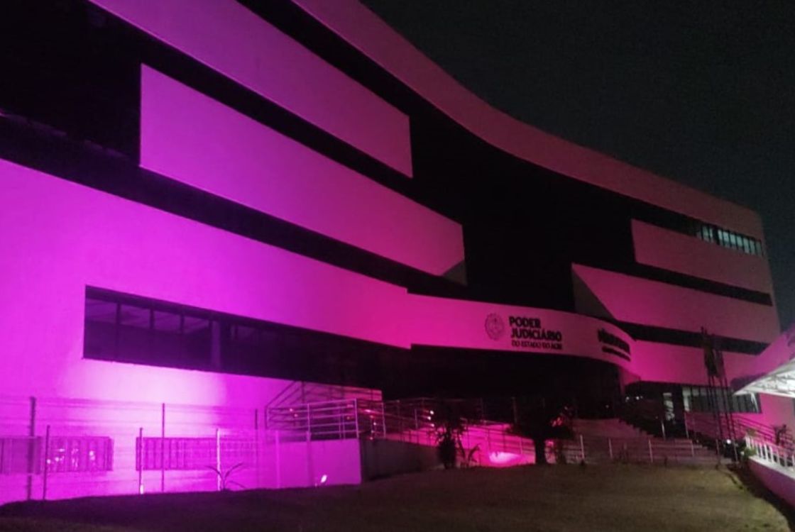 Na imagem prédio do Fórum de Juizados Especiais Cíveis iluminado com luzes de cor rosa em alusão a campanha Outubro Rosa