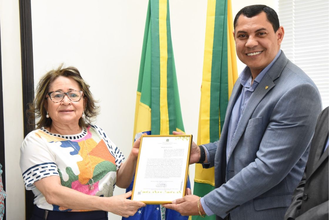 desembargadora Denise Bonfim de vestimenta branca e com cores recebe homenagem do deputado federal coronel Ulysses de vestimenta social